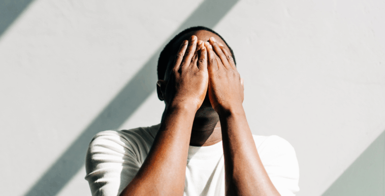 A man covering his face with his hands.