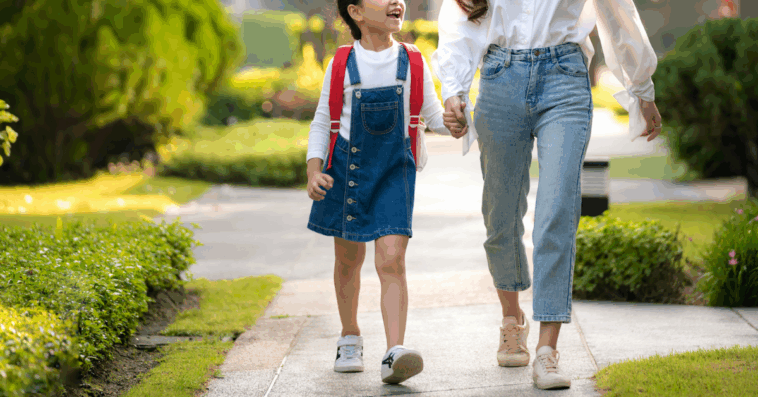 A woman holding a little girl's hand walking down the sidewalk.