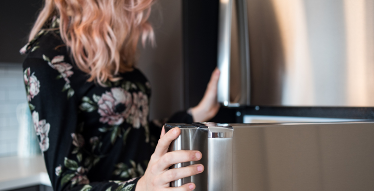 A woman peeking into a refrigerator