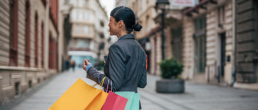 A woman walking down the streets holding shopping bags.