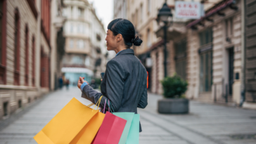 A woman walking down the streets holding shopping bags.