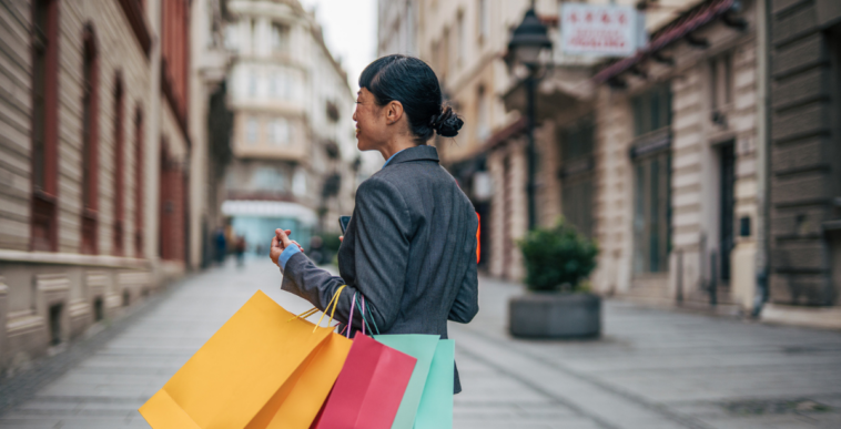 A woman walking down the streets holding shopping bags.