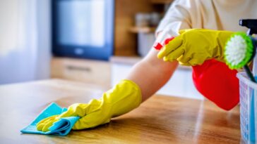 person with cleaning supplies wiping counter