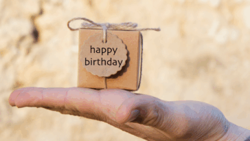 person holding small birthday gift on the palm of their hand