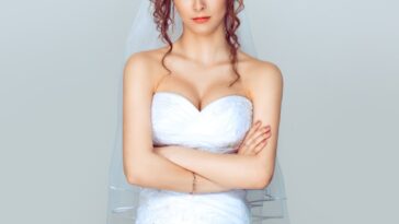 Grumpy bride. Sad and disappointed hesitating woman in wedding dress, arms folded, unhappy wife.