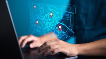 Businessman uses computer laptop to pinpoint business address on a world map with locations.