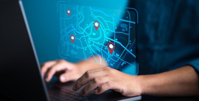 Businessman uses computer laptop to pinpoint business address on a world map with locations.