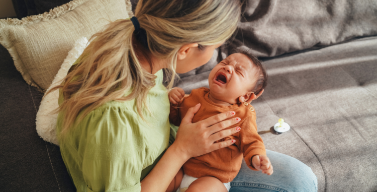 A woman holding a crying baby.
