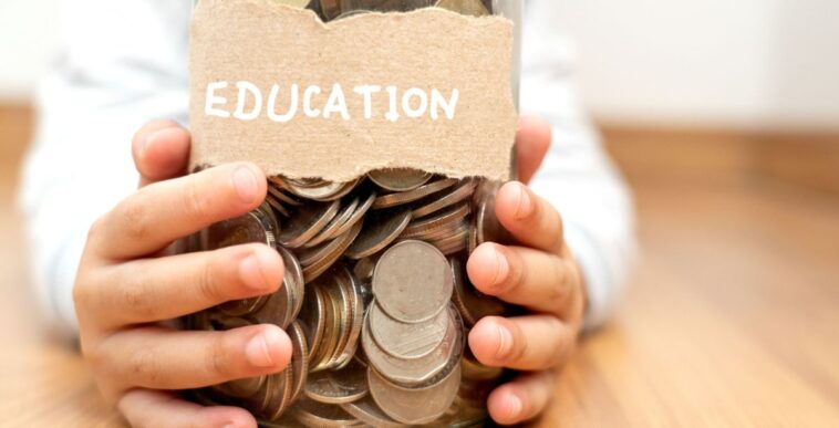 A child's hands holds a jar of coins that is labeled... "Education."