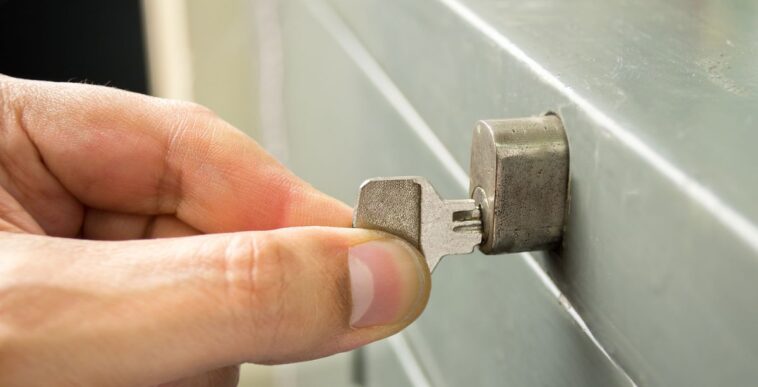 Close-up of a man's hand opening the cabinet with a key.