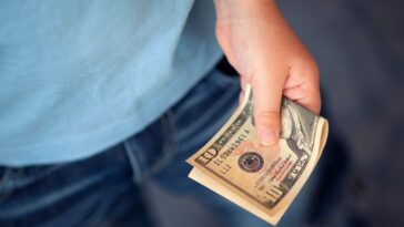 Unidentified young boy holds ten dollars.