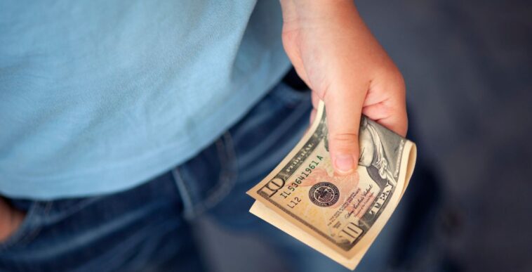 Unidentified young boy holds ten dollars.