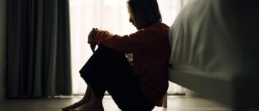 Silhouette of a woman, sad and depressed, sitting on the bedroom floor.