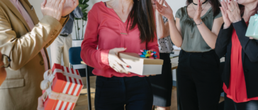 A woman being handed presents surrounded by people.