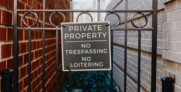 Close-up of no trespassing sign on a gate between townhouses.