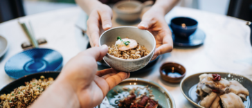 Two people sharing a number of small plates of food.