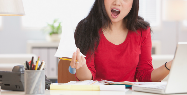 A woman sitting at a desk with a shocked expression on her face.