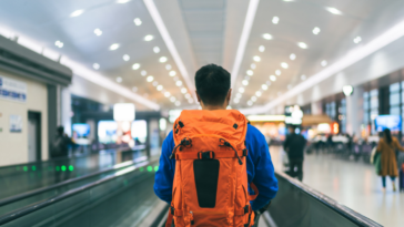 A man wearing a backpack in an airport.