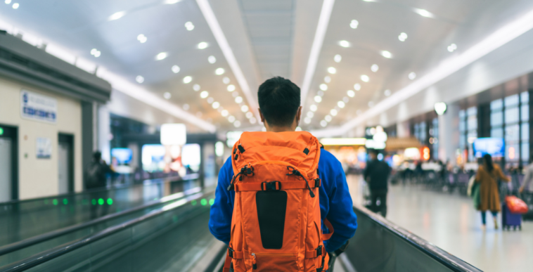 A man wearing a backpack in an airport.