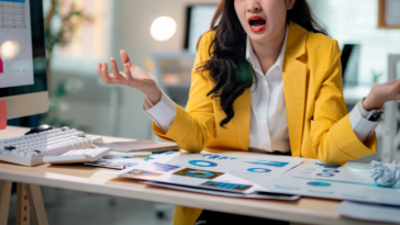An woman sitting at a desk with a distressed expression on her face.