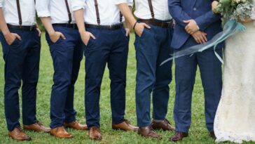 Unidentifiable groomsman pose beside a couple. The groomsmen are all wearing matching attire. Garden wedding. Concept wedding photo session.