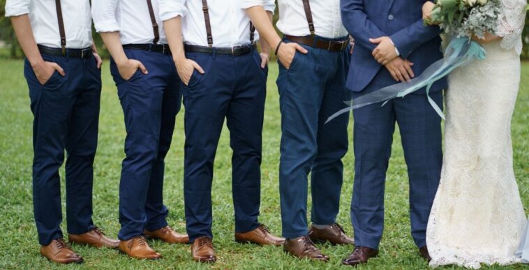 Unidentifiable groomsman pose beside a couple. The groomsmen are all wearing matching attire. Garden wedding. Concept wedding photo session.