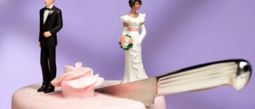 Shot of a cake topper couple, the couple is separated on top of the wedding cake by a knife cutting between them.