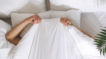 Woman hiding under her covers in bed