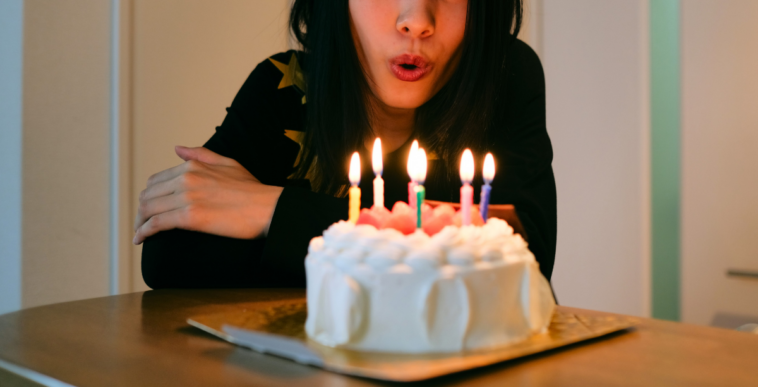 woman blowing out birthday candles on a white cake