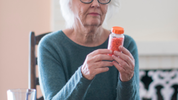 Older woman holding a prescription pill bottle