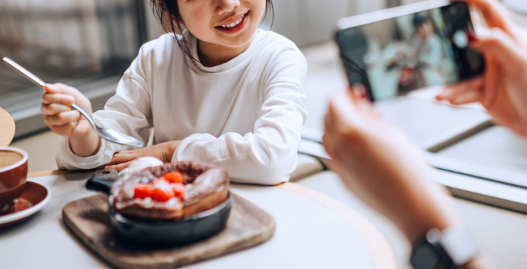woman taking photo of child eating