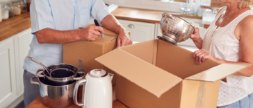 An older couple packing moving boxes.