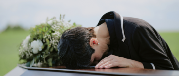 A woman crying over a casket.