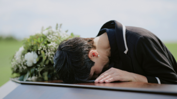 A woman crying over a casket.