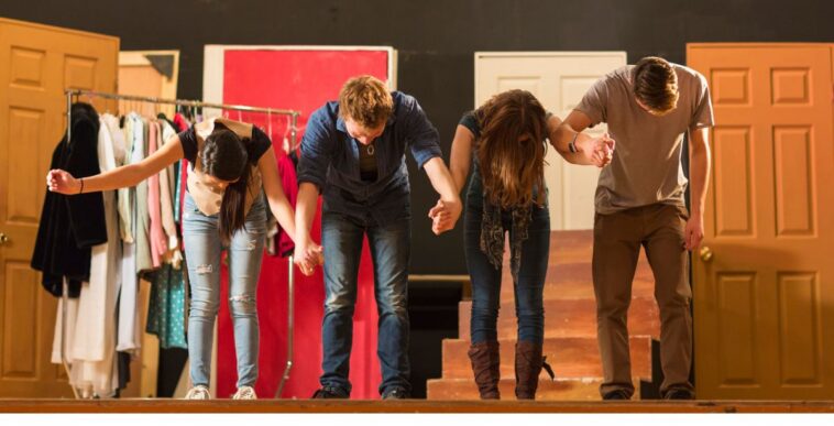 Actors holding hands on stage and bowing.
