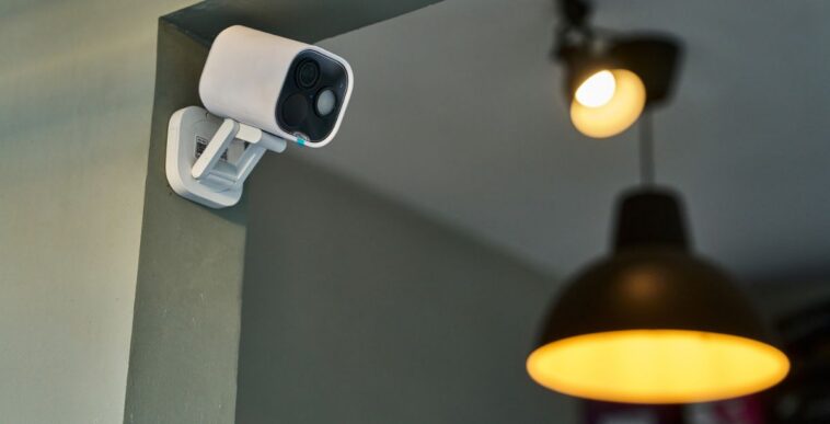 White cctv camera recording video, enhancing safety and protection in a modern interior space illuminated by warm lighting, creating a secure and inviting atmosphere.Modern wireless security camera monitoring a room.