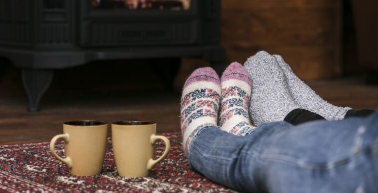 Couples warming feet in front of fireplace.
