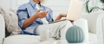 A woman sitting on a sofa with a laptop on her lap.