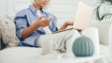 A woman sitting on a sofa with a laptop on her lap.