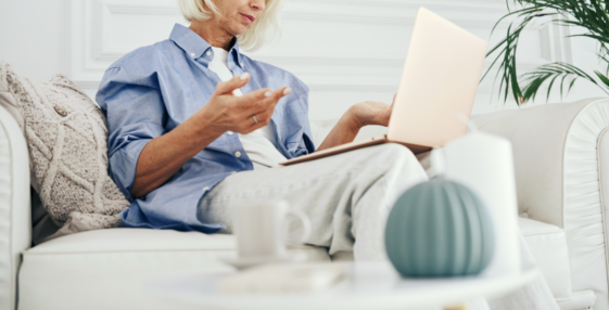 A woman sitting on a sofa with a laptop on her lap.