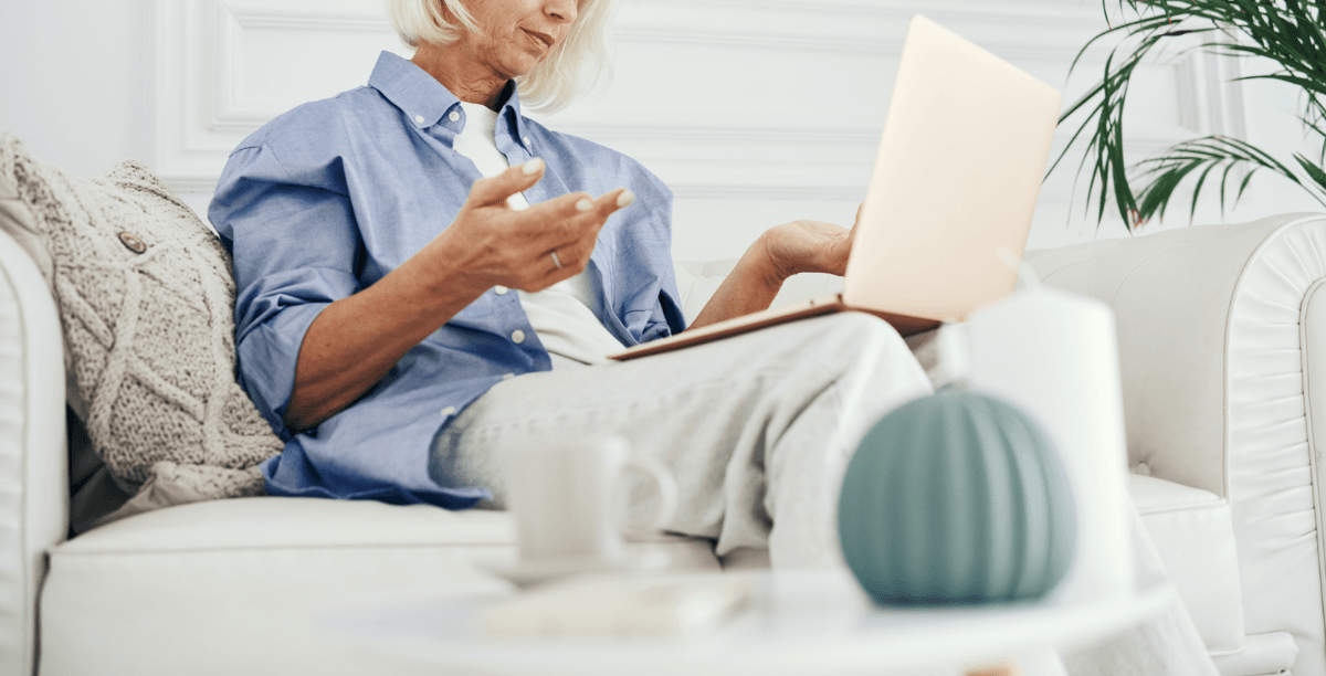 A woman sitting on a sofa with a laptop on her lap.