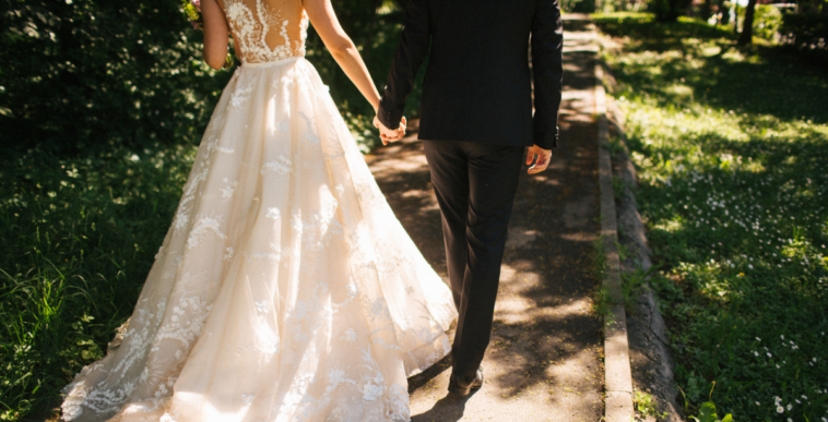 A bride and groom walking hand in hand.
