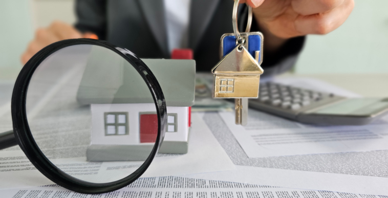 Aman holding a key above paperwork with a magnifying glass in front.