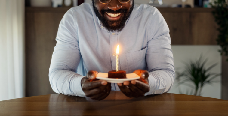 A man holding a plate with a candle in it.