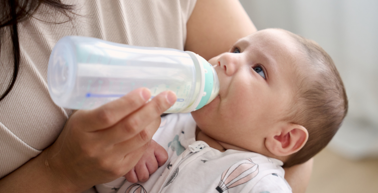 A woman feeding a baby with a bottle.