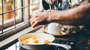 A man cooking eggs om a stoveop.