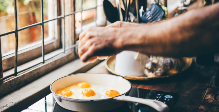 A man cooking eggs om a stoveop.