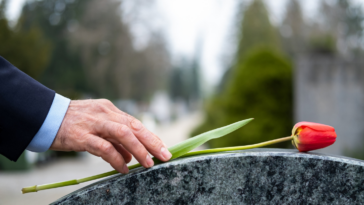 A man putting a rose on a grave.