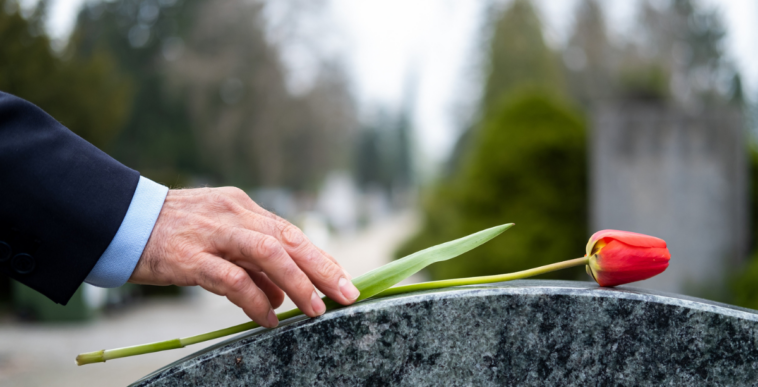 A man putting a rose on a grave.