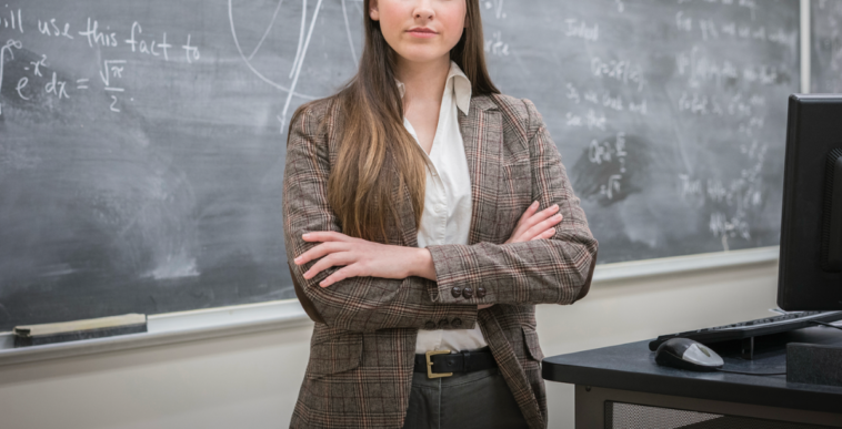 A woman standing in front of a chalk board with her arms crossed.